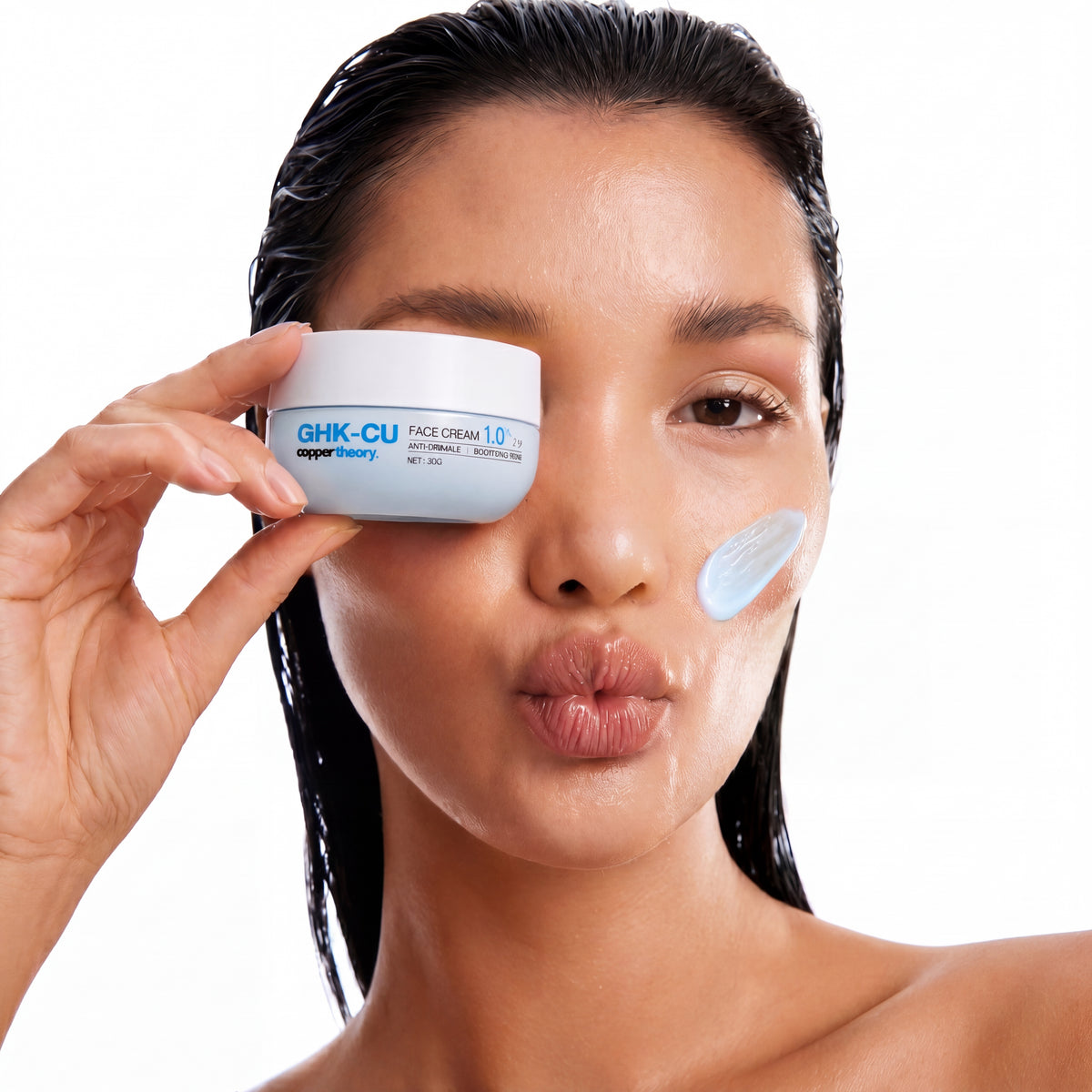 Model holding CopperTheory GHK-Cu copper peptide face cream with light blue cream applied to the cheek